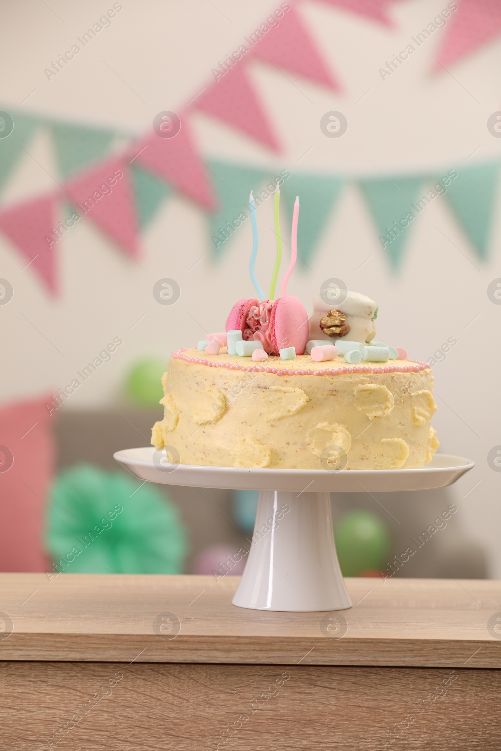 Photo of Delicious cake decorated with macarons and marshmallows on wooden table against blurred background