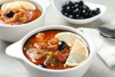 Photo of Meat solyanka soup with sausages, olives and vegetables on white table, closeup