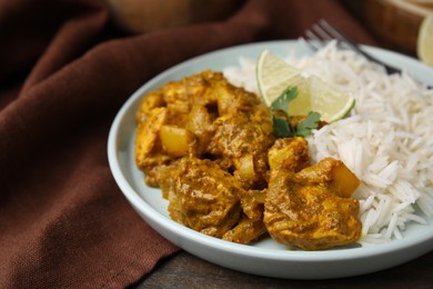 Photo of Delicious chicken curry with rice on wooden table, closeup