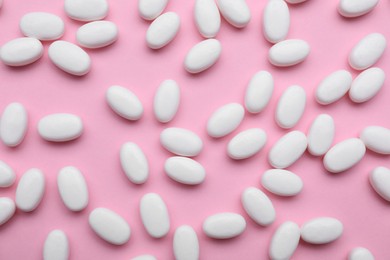 Photo of Many white dragee candies on pink background, flat lay