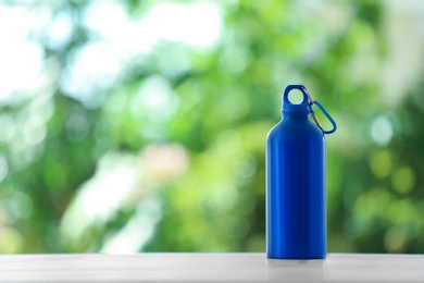 Photo of Sports water bottle on table against blurred background. Space for text