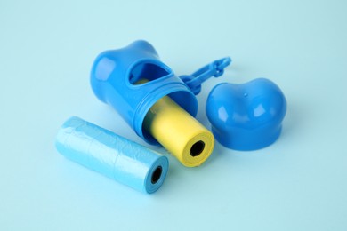Photo of Dog waste bags and dispenser on light blue background