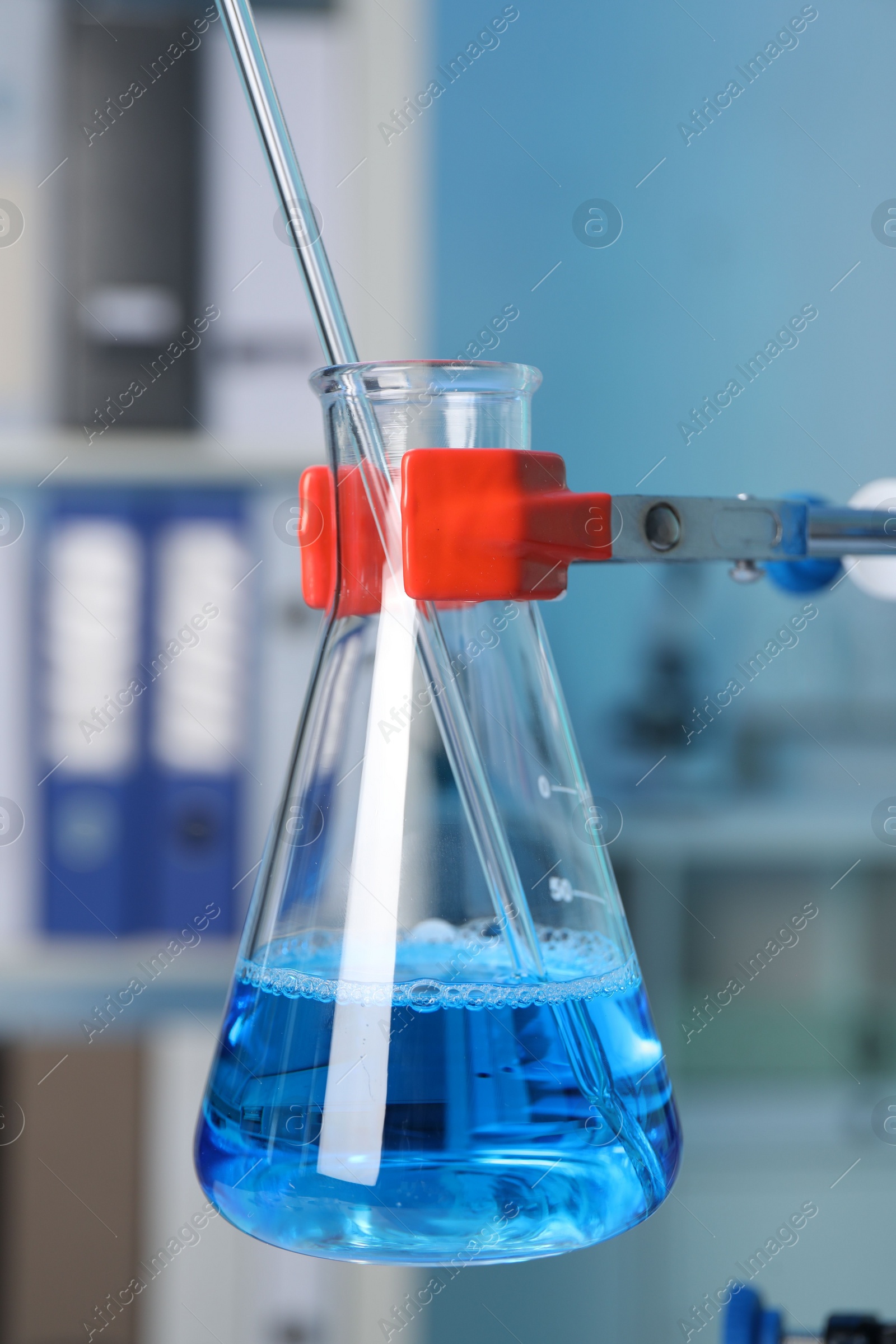 Photo of Laboratory analysis. Glass flask with blue liquid on stand indoors, closeup