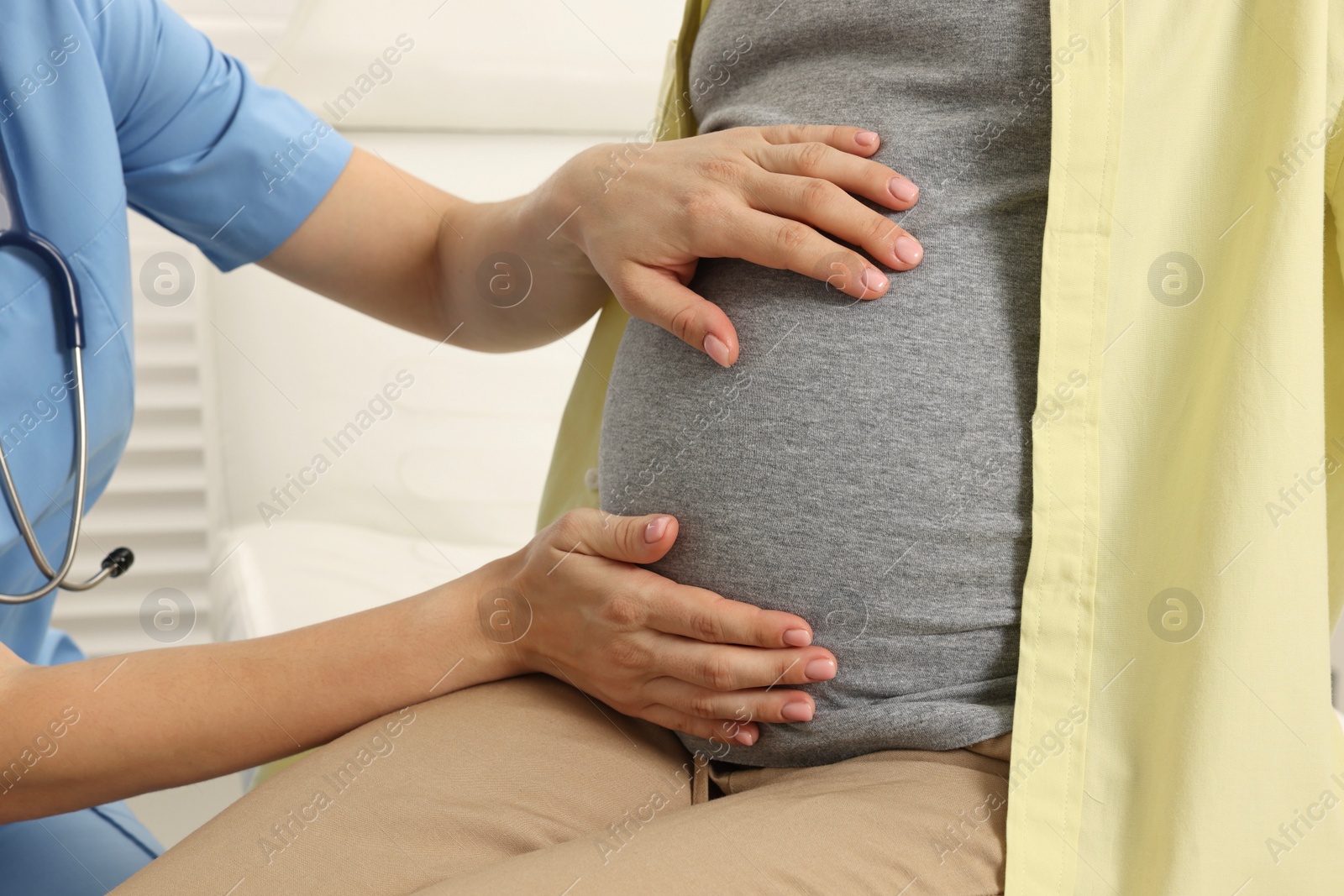 Photo of Pregnancy checkup. Doctor examining patient's tummy in clinic, closeup