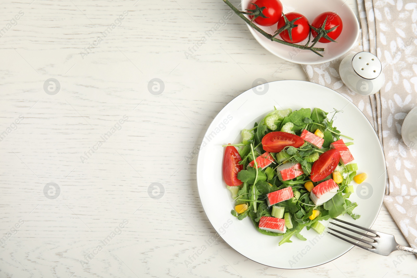 Photo of Tasty crab stick salad served on white table, flat lay. Space for text