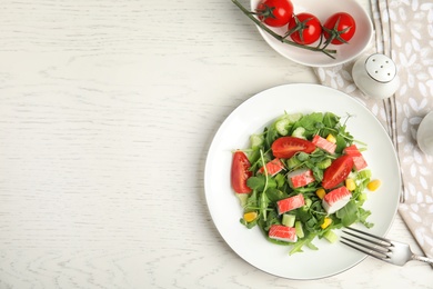 Tasty crab stick salad served on white table, flat lay. Space for text