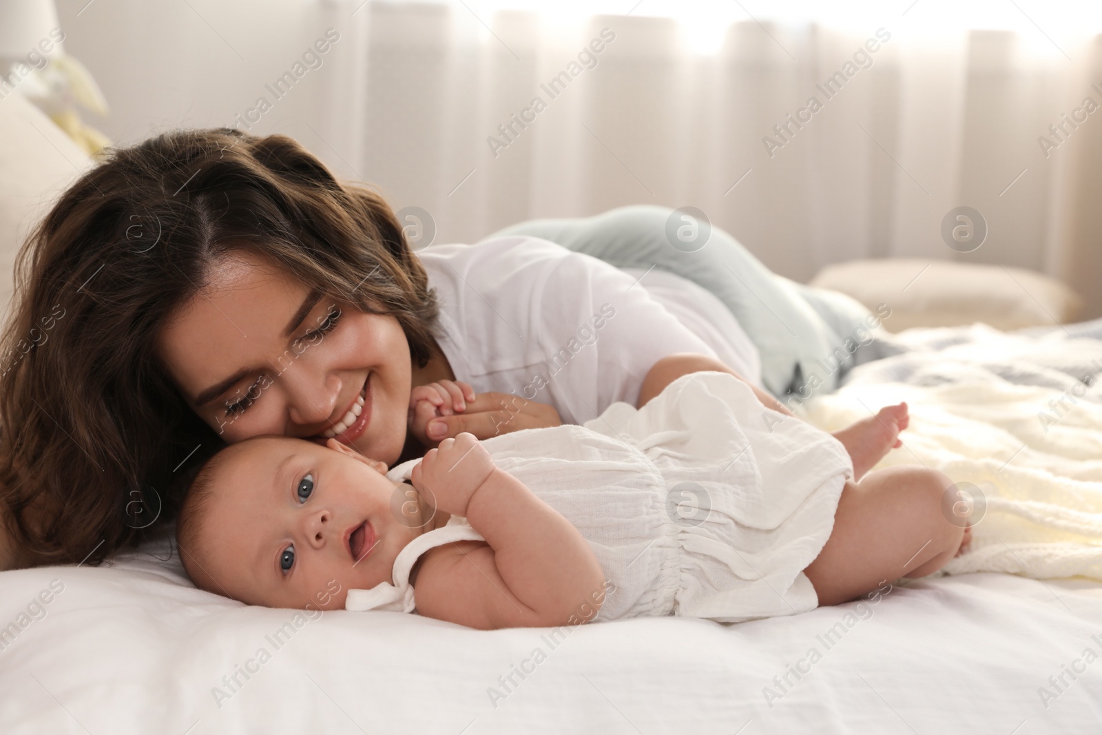 Photo of Happy young mother with her cute baby on bed at home