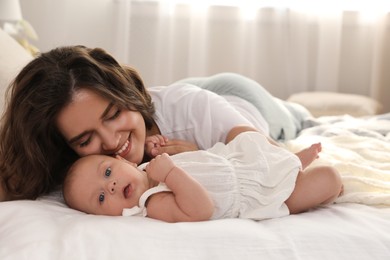 Photo of Happy young mother with her cute baby on bed at home