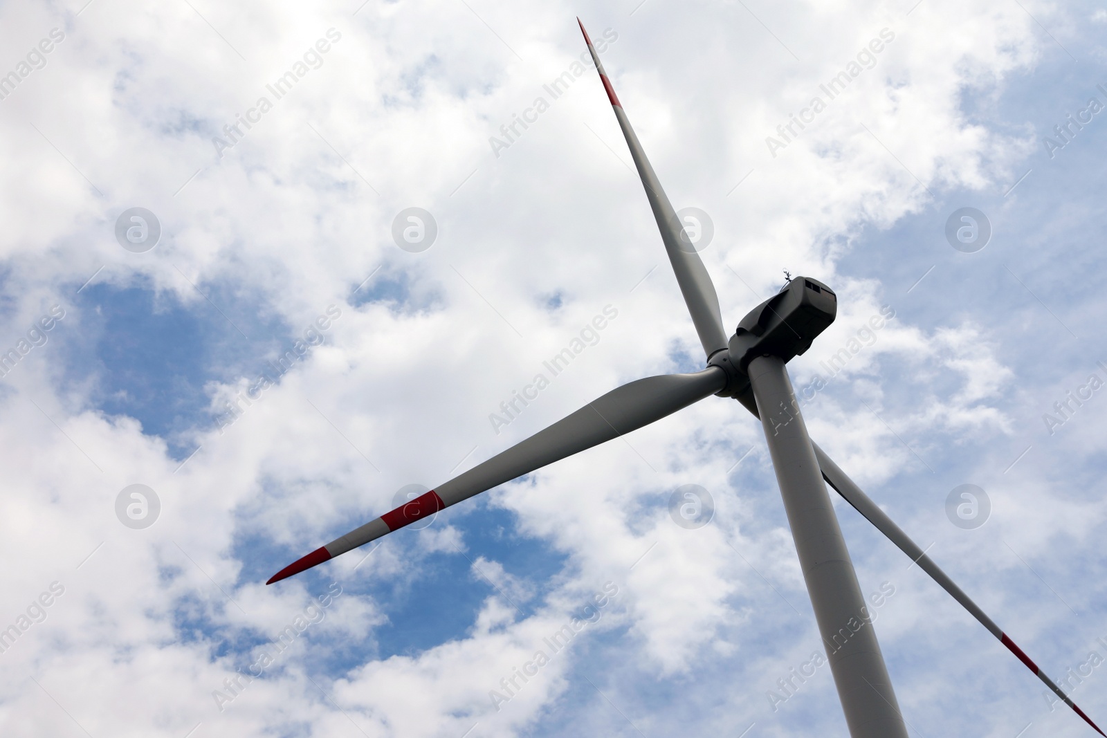 Photo of Modern wind turbine against cloudy sky, closeup. Alternative energy source