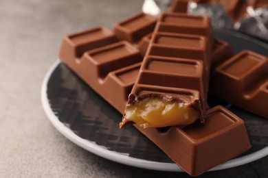 Plate with tasty chocolate bars on grey table, closeup. Space for text