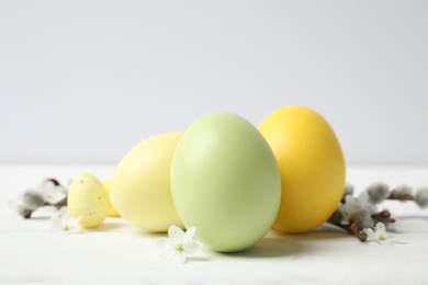 Photo of Colorful Easter eggs and flowers on white wooden table