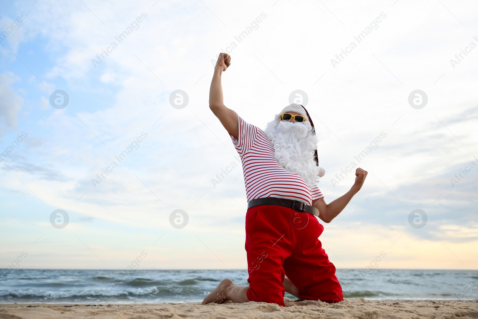 Photo of Santa Claus having fun on beach, space for text. Christmas vacation