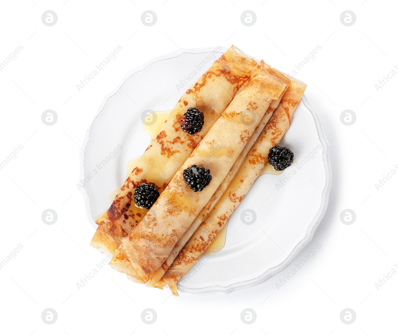 Photo of Tasty thin pancake rolls with blackberries on plate against white background, top view