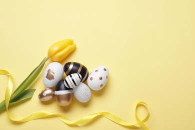 Photo of Flat lay composition with tulip and beautifully painted eggs on yellow background, space for text. Easter celebration