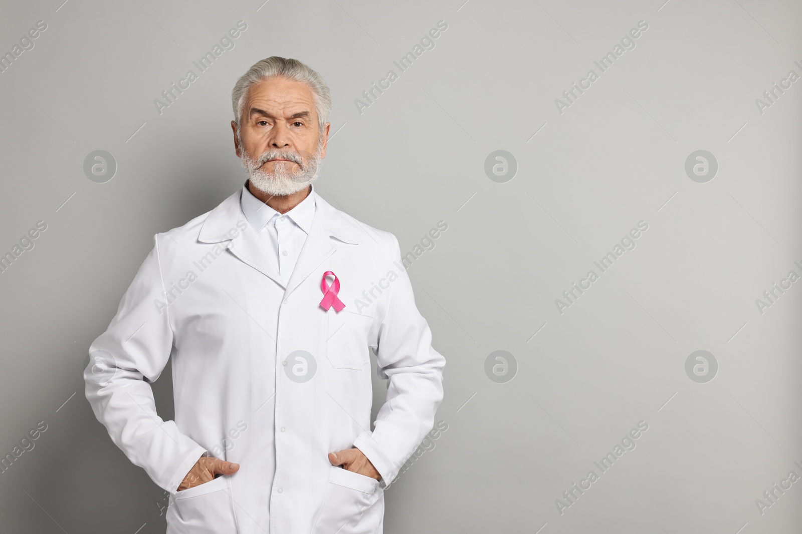 Photo of Mammologist with pink ribbon on gray background, space for text. Breast cancer awareness