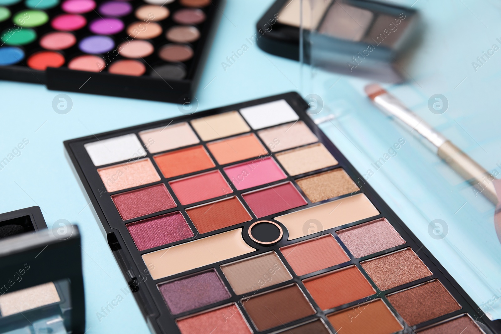 Photo of Beautiful eye shadow palettes on light blue background