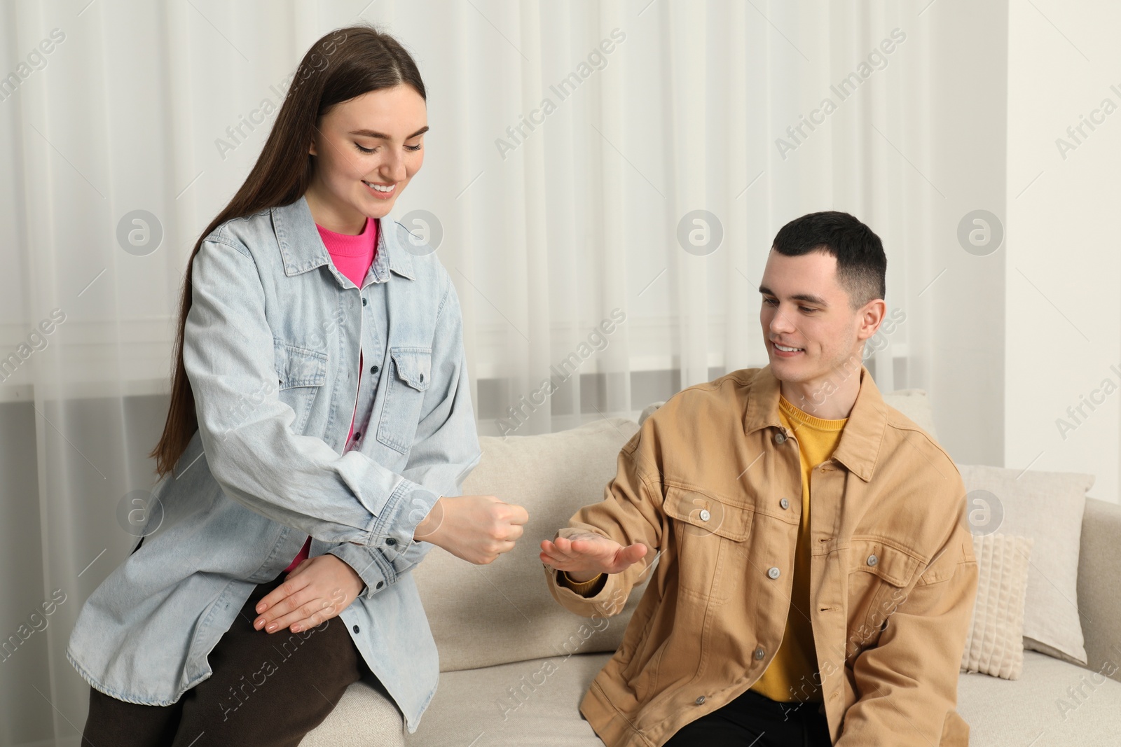 Photo of Happy people playing rock, paper and scissors in room