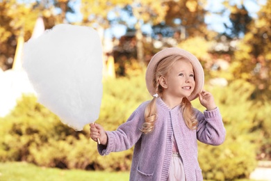 Photo of Cute little girl with cotton candy outdoors