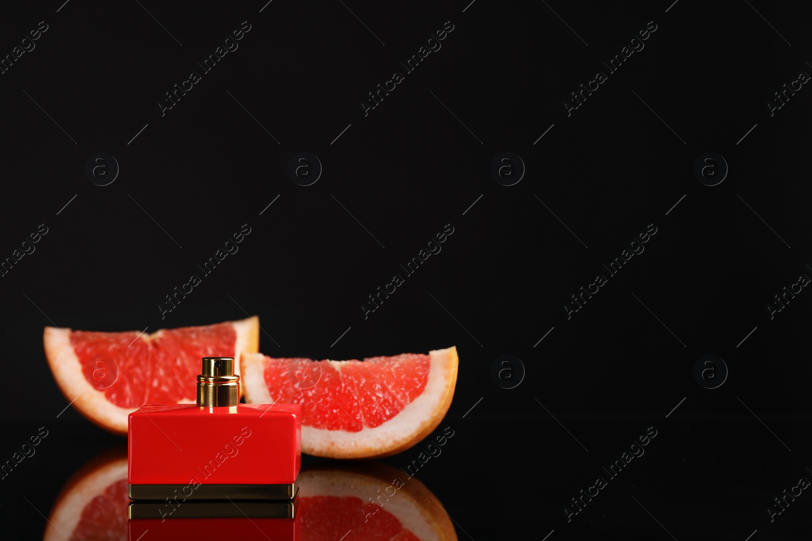 Photo of Perfume bottle and slices of citrus fruit on black background