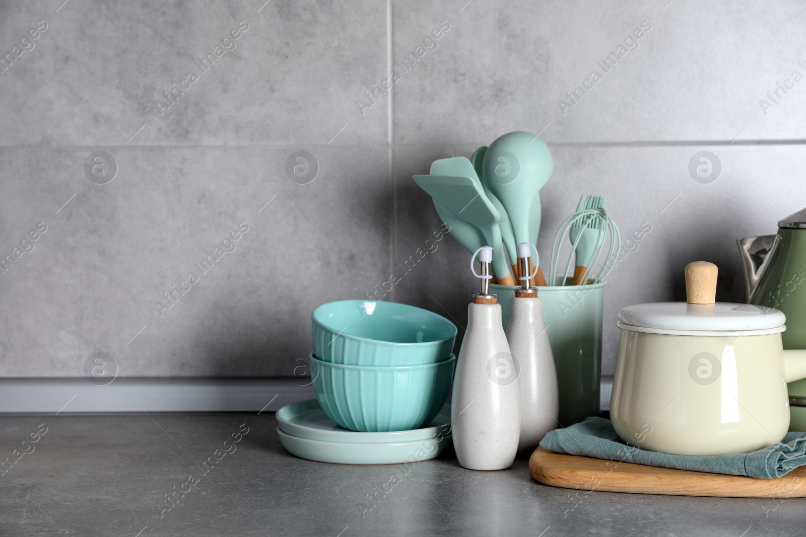 Photo of Set of different cooking utensils on grey countertop in kitchen. Space for text