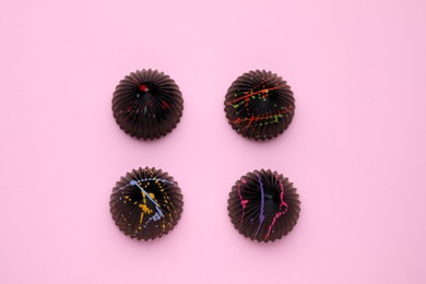 Different tasty chocolate candies on pink background, flat lay
