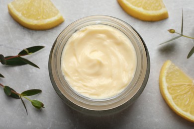 Photo of Jar of organic cream and lemon slices on light marble table, flat lay