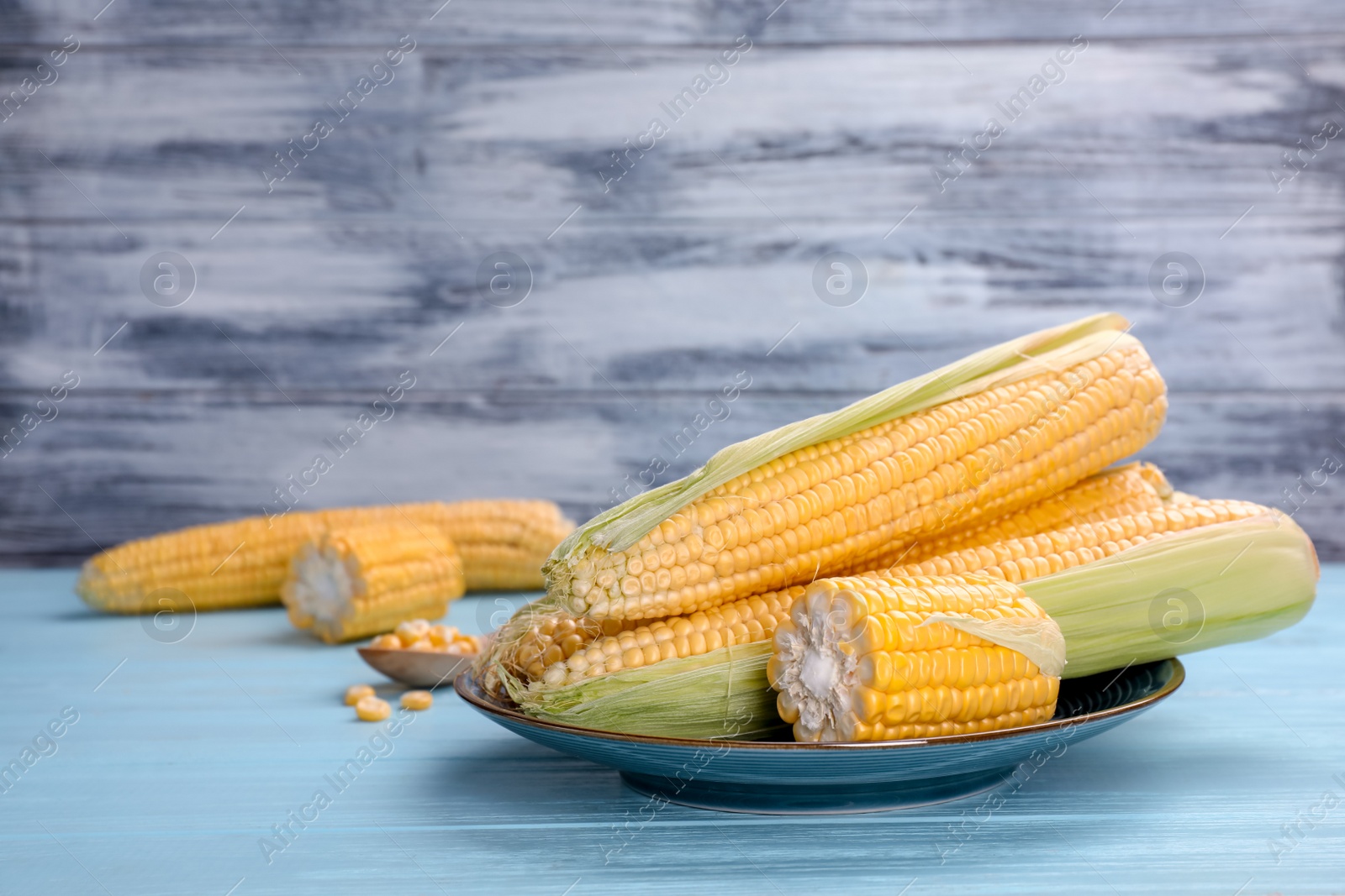 Photo of Plate with tasty sweet corn cobs on wooden table