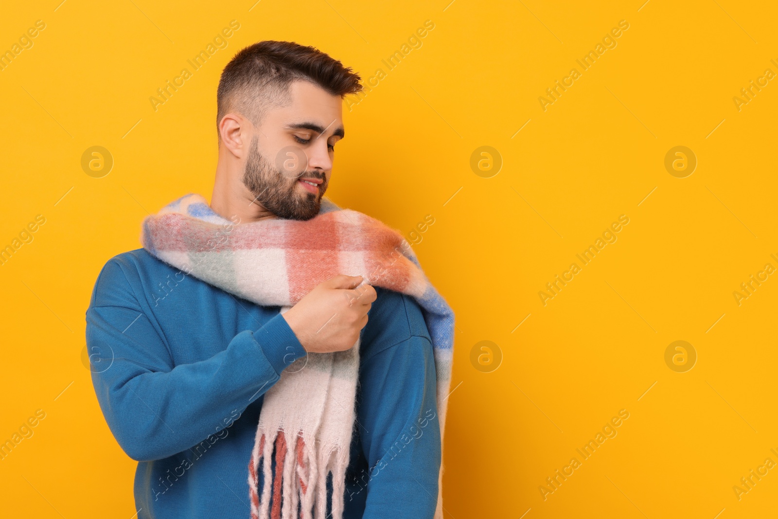 Photo of Handsome man in warm scarf on yellow background. Space for text