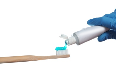 Photo of Dentist squeezing paste onto toothbrush on white background