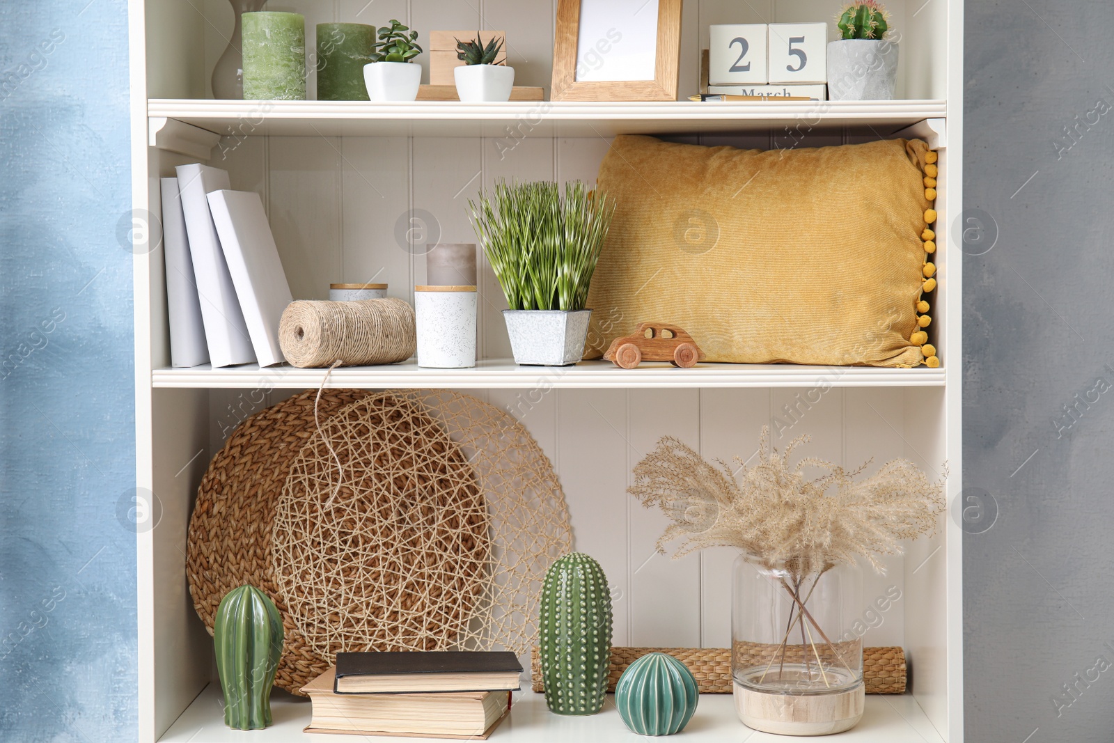 Photo of White shelving unit with plants and different decorative stuff