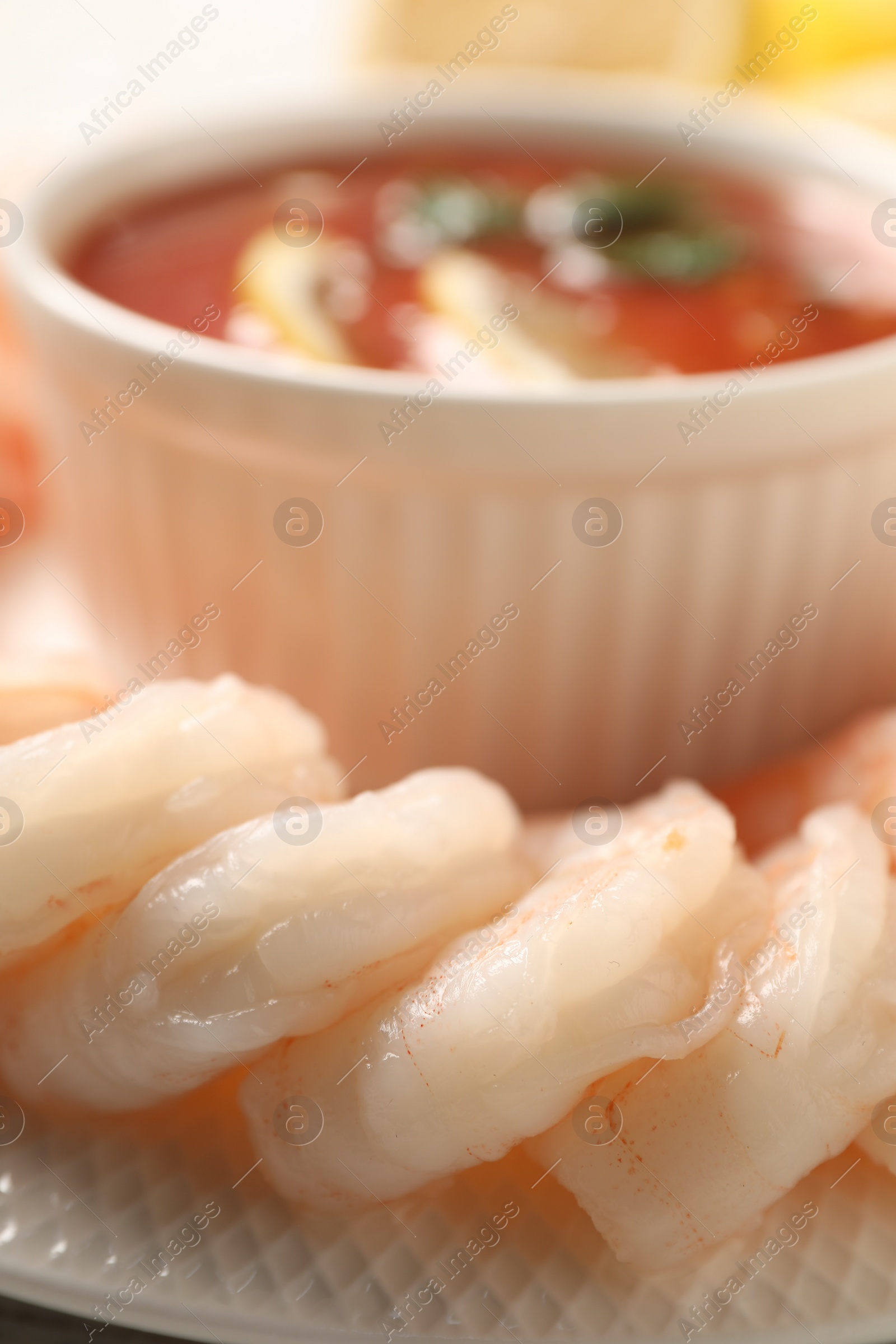 Photo of Tasty boiled shrimps with cocktail sauce and lemon on plate, closeup