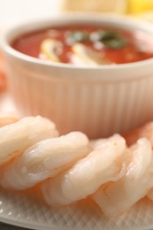 Photo of Tasty boiled shrimps with cocktail sauce and lemon on plate, closeup