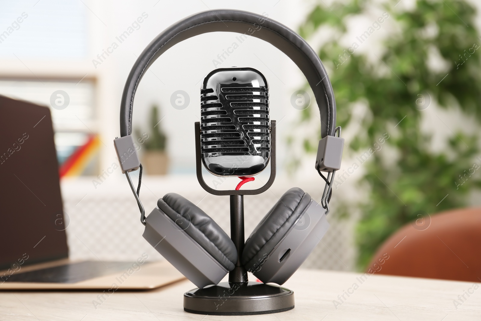 Photo of Microphone, modern headphones and laptop on table indoors