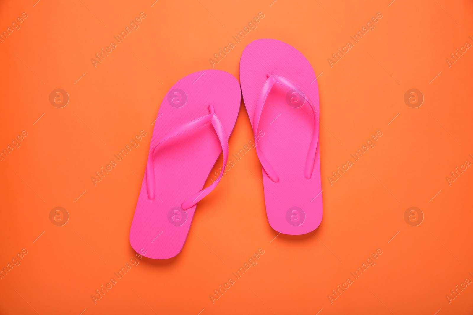 Photo of Stylish pink flip flops on orange background, top view