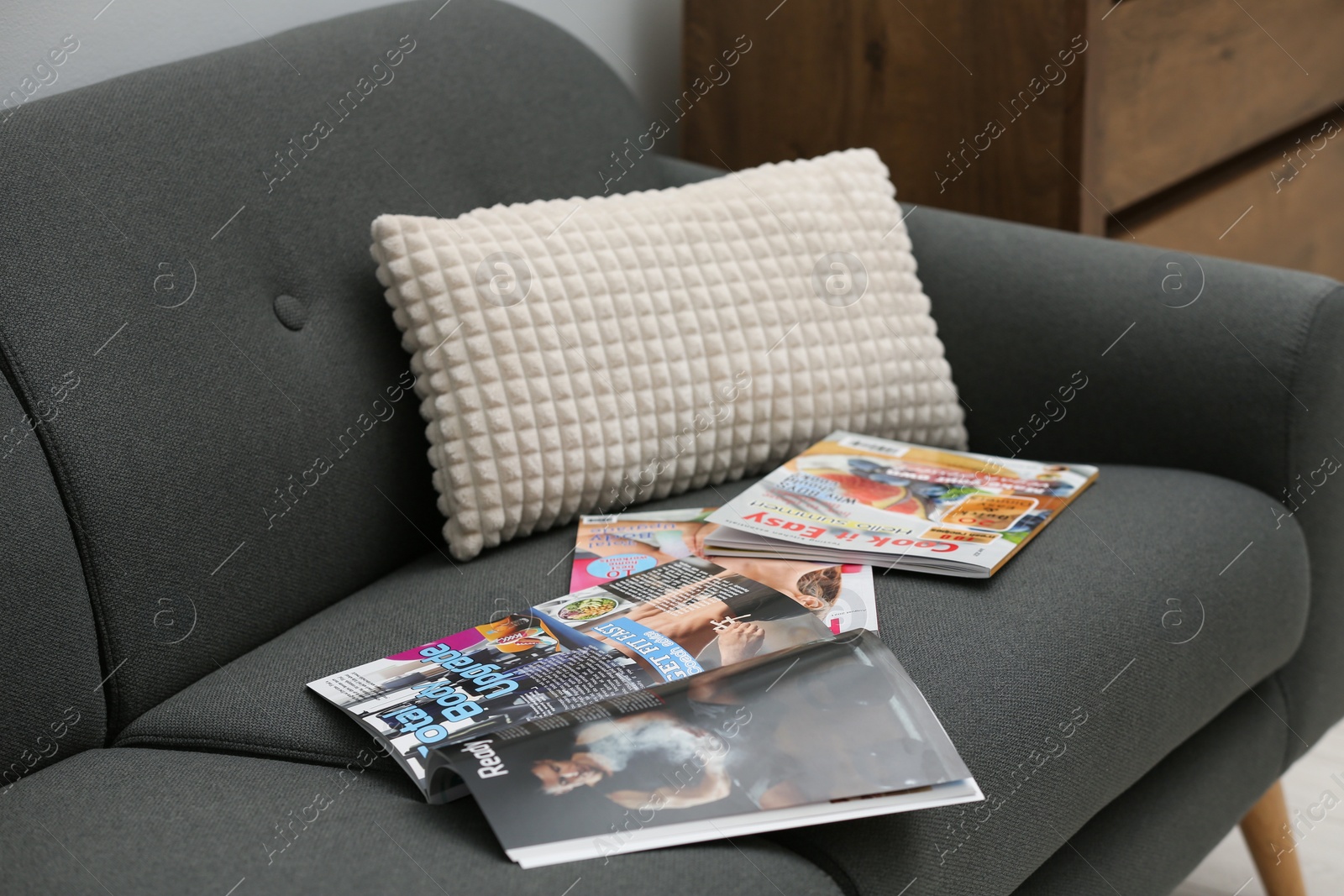 Photo of Different magazines on sofa in living room