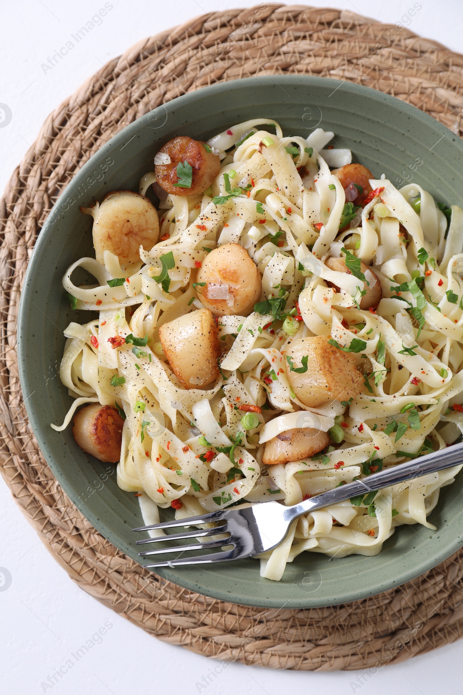 Photo of Delicious scallop pasta with spices in bowl served on white table, top view