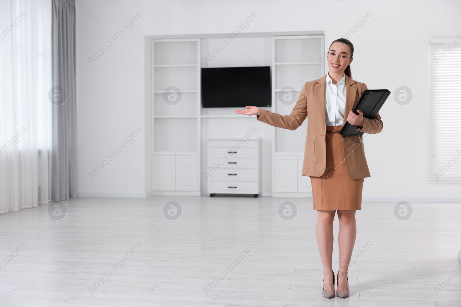 Photo of Happy real estate agent with leather portfolio showing new apartment