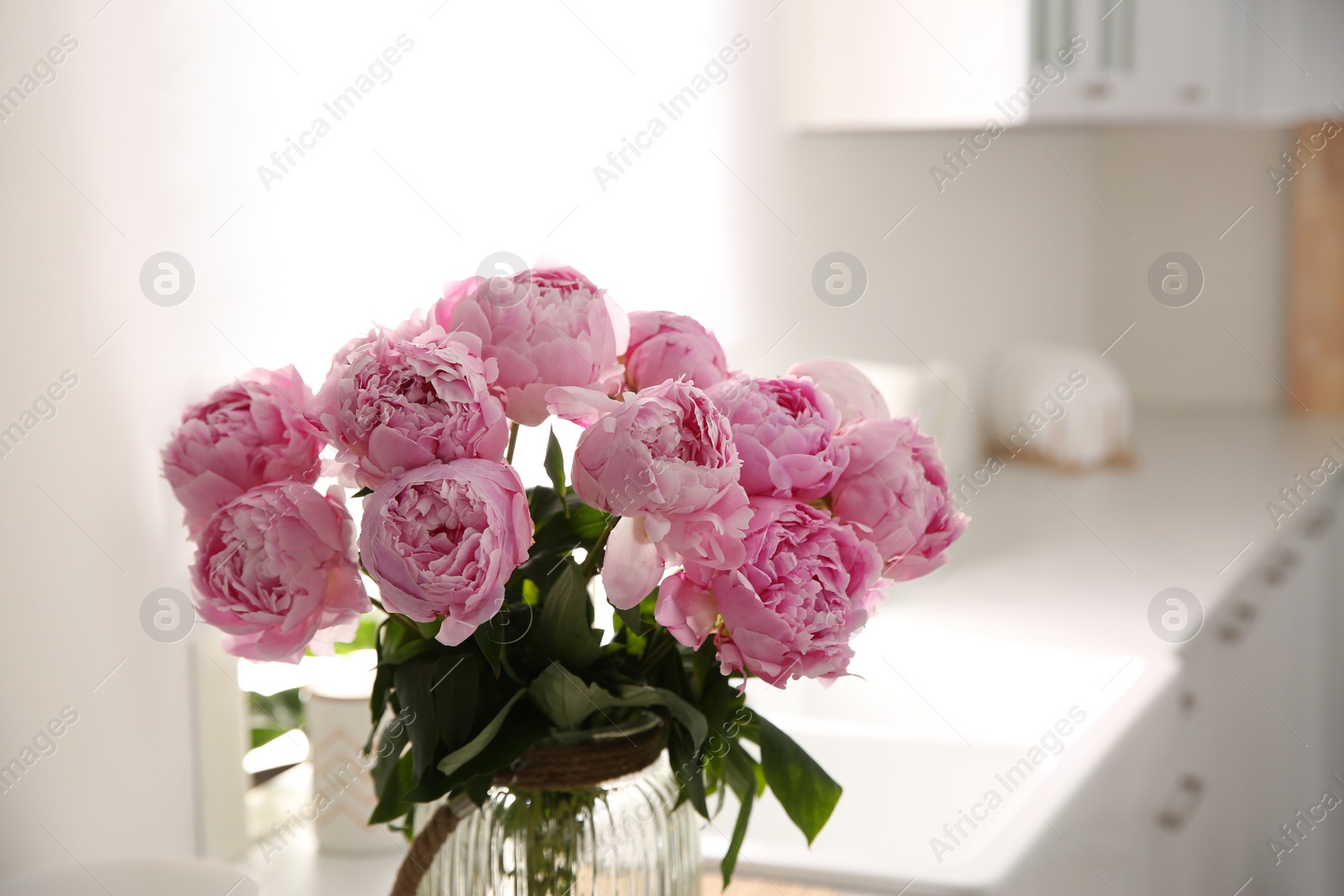 Photo of Vase with bouquet of beautiful pink peonies in kitchen