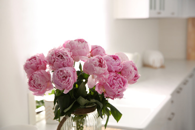 Photo of Vase with bouquet of beautiful pink peonies in kitchen