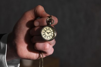 Photo of Man holding chain with elegant pocket watch, closeup. Space for text