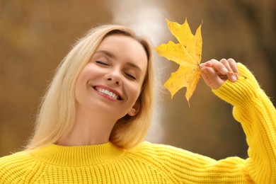 Photo of Portrait of happy woman with autumn leaf outdoors