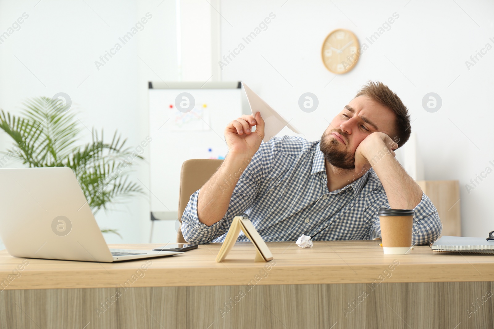 Photo of Lazy office employee playing with paper plane at workplace