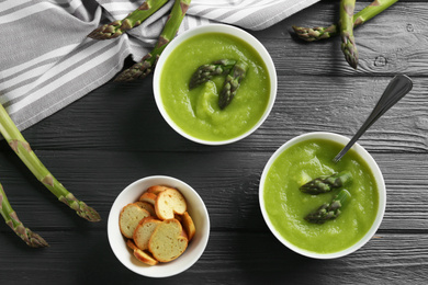 Photo of Delicious asparagus soup served on grey wooden table, flat lay