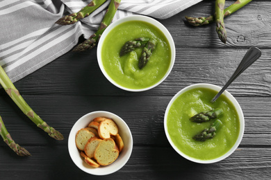 Delicious asparagus soup served on grey wooden table, flat lay