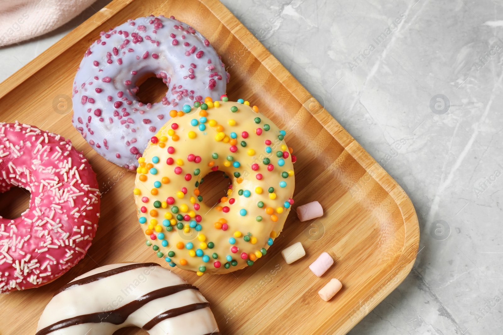 Photo of Yummy donuts with sprinkles on marble table, top view