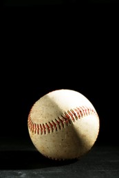 Old worn baseball ball on black background