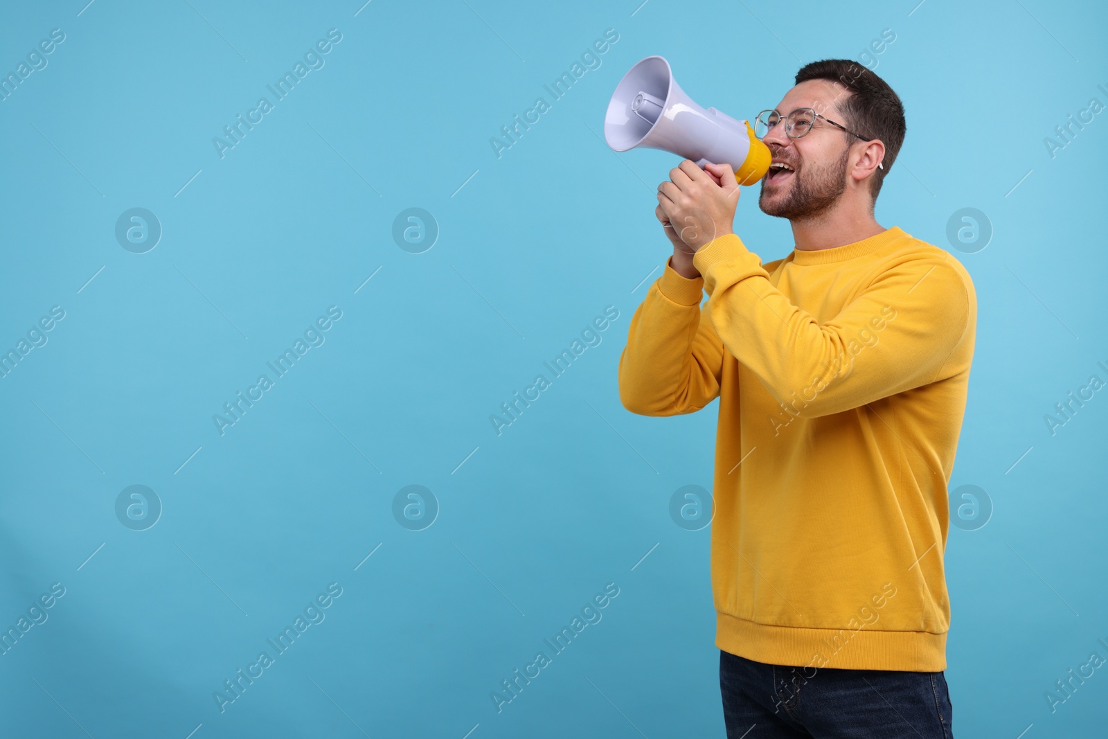 Photo of Special promotion. Man shouting in megaphone on light blue background. Space for text