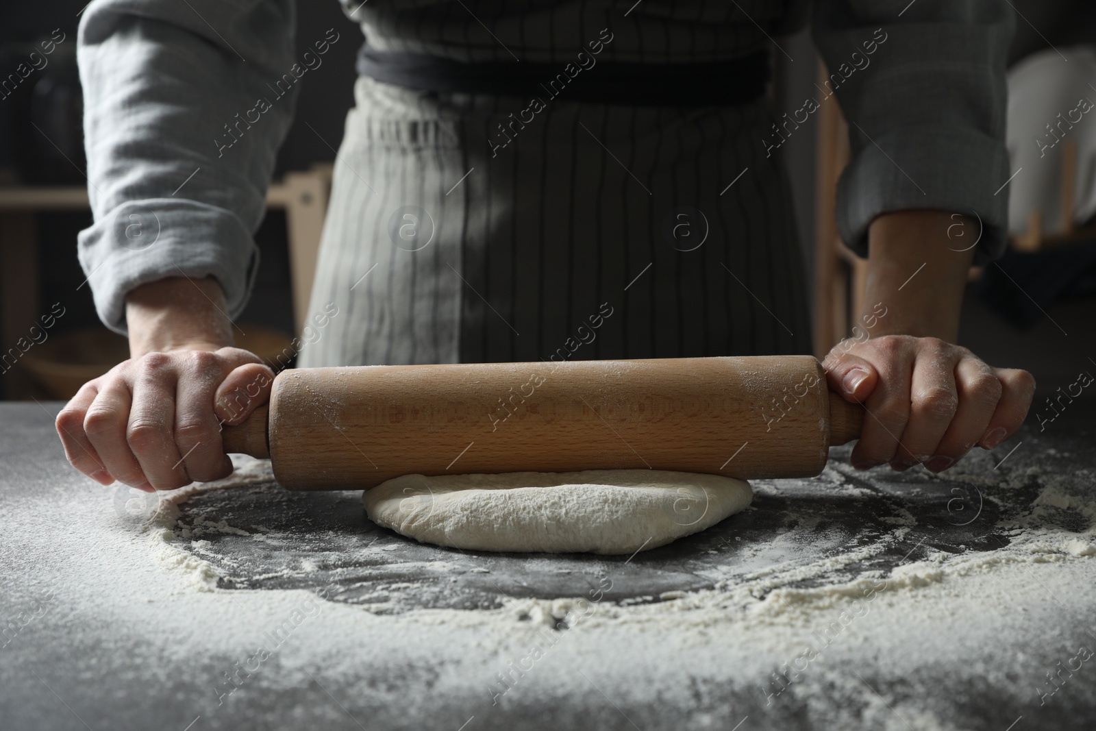 Photo of Woman rolling pizza dough with pin at table, closeup