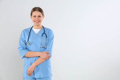 Photo of Young doctor with stethoscope against light background
