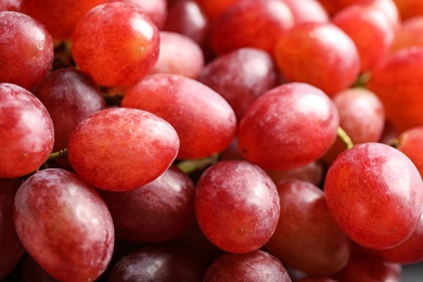 Fresh ripe juicy pink grapes as background, closeup view